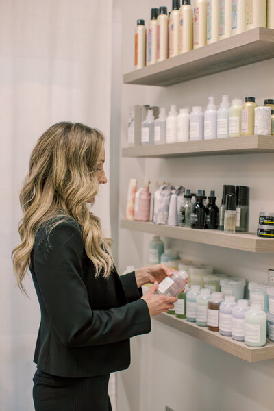 Person holding shampoo bottle next to wall of products