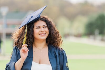 Quinnipiac university graduate holds her tassel of her cap and smiles.