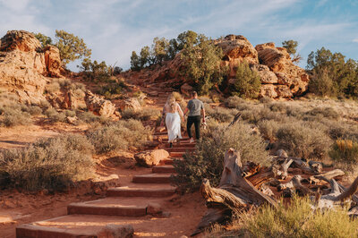 A couple walks hand in hand up stone steps