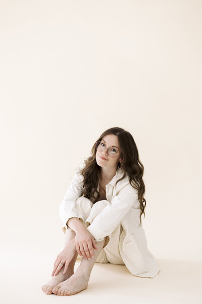 woman sits with arms crossed over knees