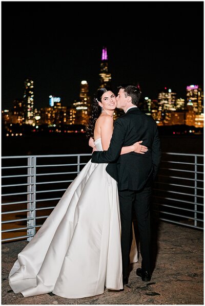 Night portrait of bride and groom outside the Adler Planetarium overlooking the Chicago skyline.