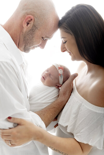 smiling mom and dad holding their baby girl newborn
