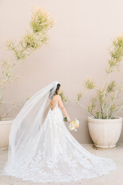 Bride in front of neutral wall with gown and bouquet
