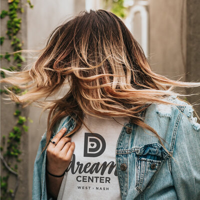 Woman wearing a denim jacket with a tshirt with the Dream Center logo.