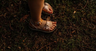 a toddles sister who’s kissing and hugging a newborn baby that is sleeping