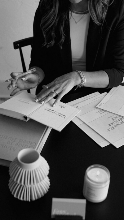 Monochrome image of a stylish woman working at a modern desk with black-and-white office decor, candles, and notebooks