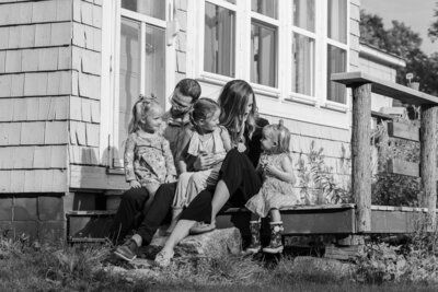 Family sitting on porch, parents looking at kids | Family session