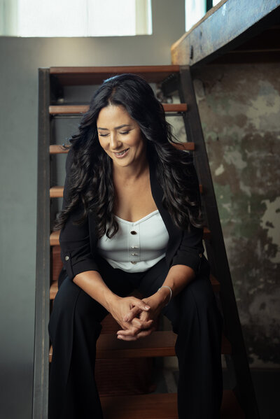 Portrait of Asmahan, a strategic online business manager, sitting confidently in a neutral dress against a stone backdrop