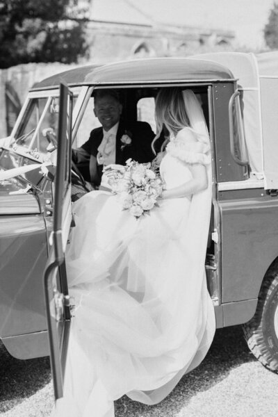 bride and groom sitting in the wedding car, bride dress train flowing out of car