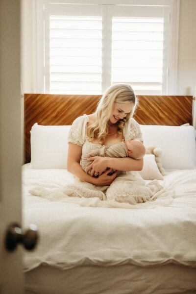newborn photo on a tiny swaddled baby. the baby in centered in the frame and is holding each of her parents hands