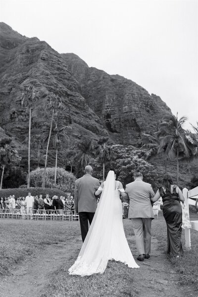 A group of people walking a wedding participant down the aisle 