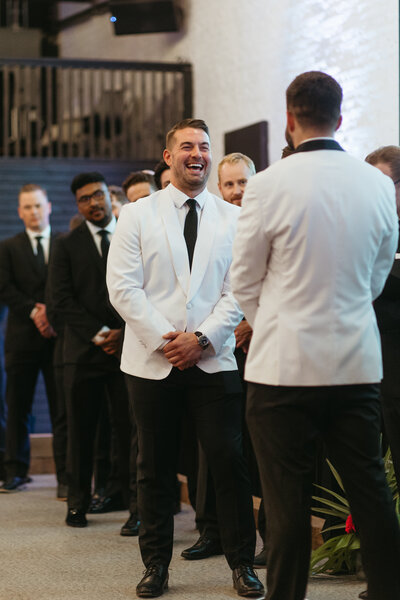 Two grooms smiling at each other at their wedding.
