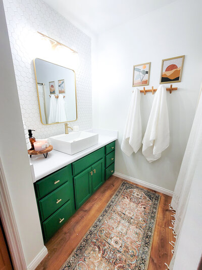 a master bathroom with green cabinets and white countertops
