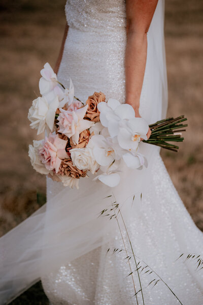 Close up of bridal bouquet containing roses and singapore orchids.