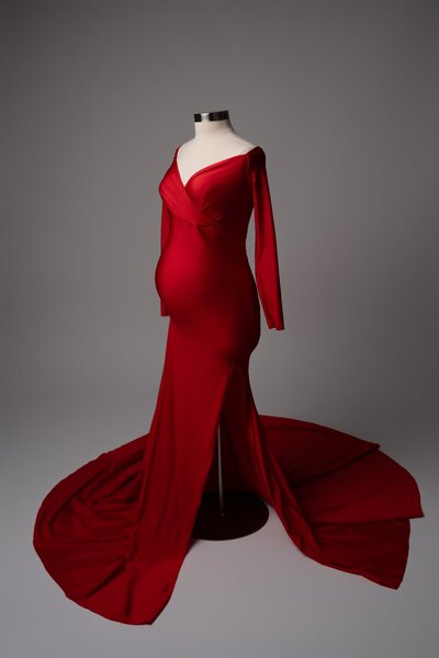 Fitted red maternity gown with off-shoulder neckline and long train on mannequin – available at Austin photo studio
