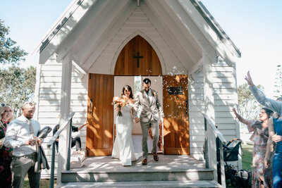 Bride and groom leaving Man O’ War chapel on Waiheke Island, New Zealand, photographed by Zanthe Vorsatz.