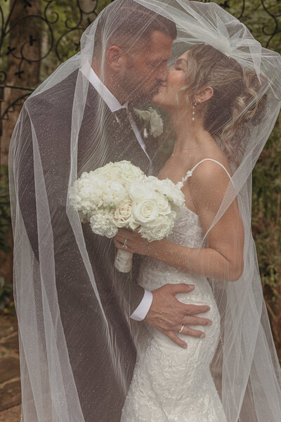 A groom kisses his wife under her veil in placerville