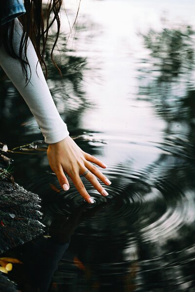 Woman lightly touching water creating a ripple effect