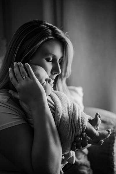 A mother gently holds her newborn baby, capturing a serene and intimate moment of their early connection.