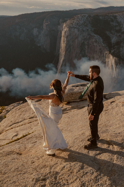 Bride twirling groom on top of Taft Point in Yosemite at sunset with view of El Capitan