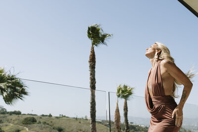 Aine Rock in a dress on a balcony with palm trees in the background 