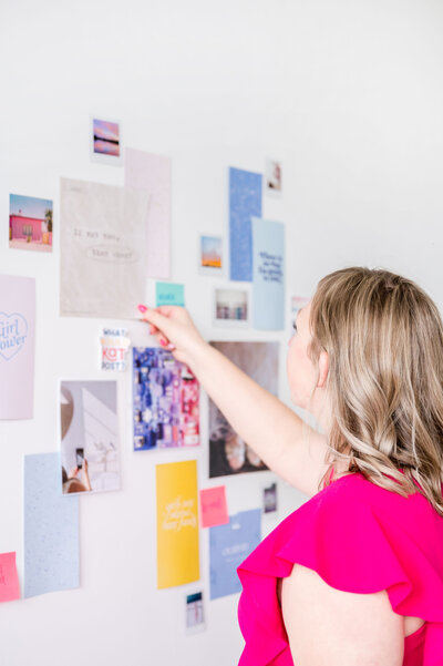 Kat Murphy putting pieces of paper onto a collage wall