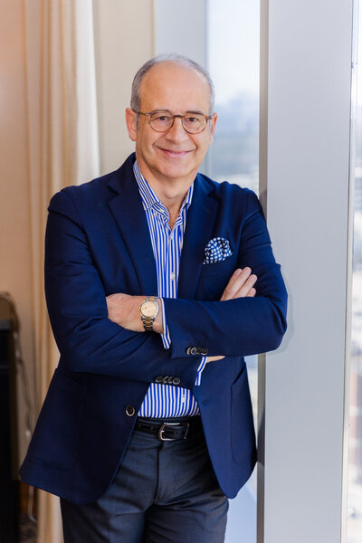 Ahmet Bozer wearing a formal outfit leaning against a window with arms crossed during a personal brand session in Buckhead Atlanta