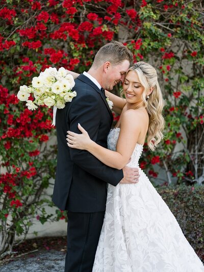 couple kissing in front of red flowers by south jersey wedding planners