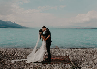 Mt Cook elopement NZ - couple kissing at wedding with turquoise water and snow covered mountains in the background