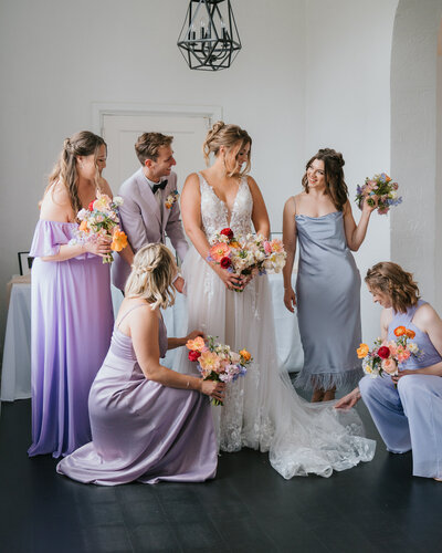 Bridesmaids adoringly looking at bride in lilac dresses and colorful flowers at Kansas City wedding venue La Villa.
