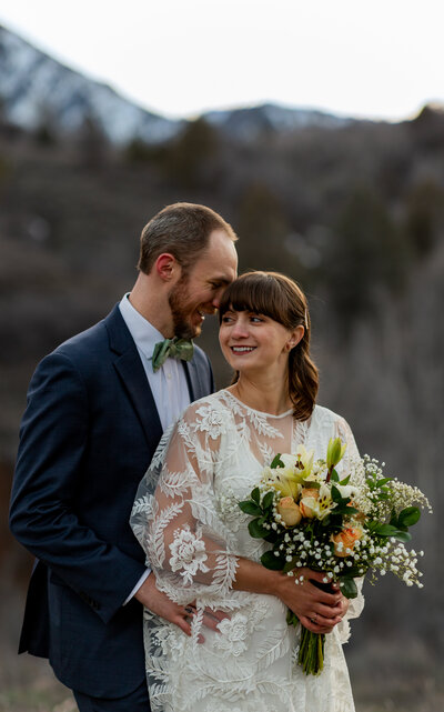 Groom standing behind bride holding her waist as they both laugh