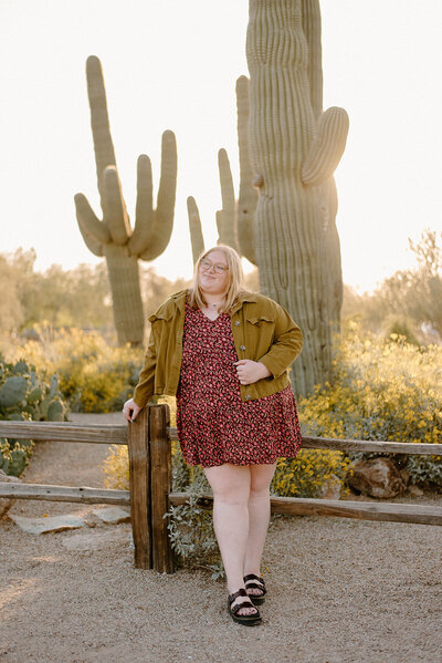 Asu graduate leaning against a wooden fence at Riparian Preserve