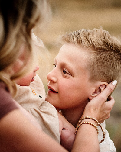 Mother looking into her young sons eyes who is smiling back at her. 