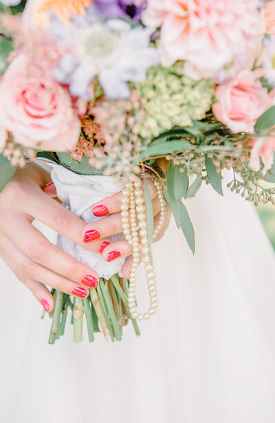 Bride's hands holding wedding bouquet with pearls
