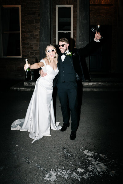 Bride and groom pholding champagne bottles after their wedding at the Kilshane House in Tipperary, Ireland
