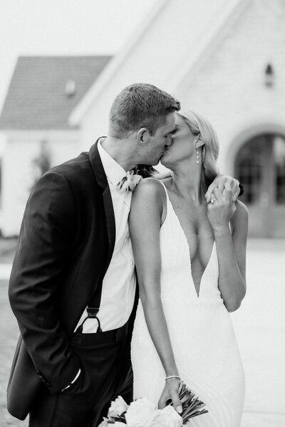 groom wraps his arm around bride as they kiss over her shoulder