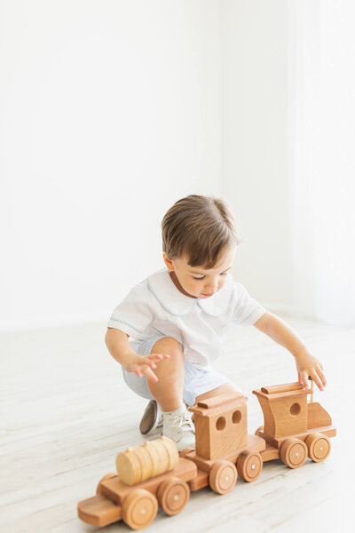 Little boy playing with a wooden toy train