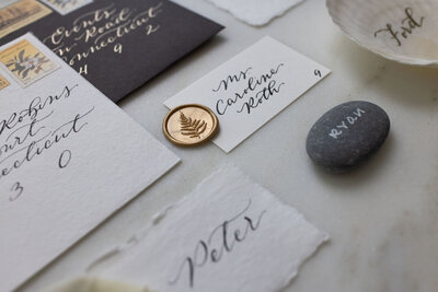 Wedding escort card with black ink calligraphy and gold wax seal