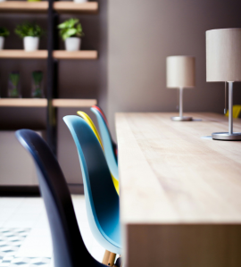 Modern, colorful chairs at a shared workspace table, representing inclusion, diversity, and collaboration in the workplace.