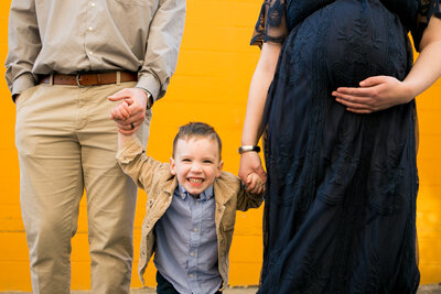 Photo of Parents holding son's hand and Mom holding pregnant belly | Maternity Session