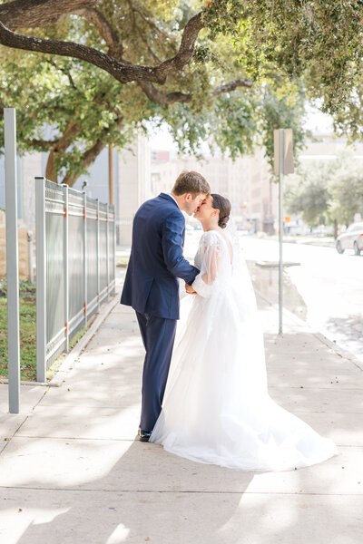 San Antonio wedding photographer captures bride and groom kissing on a downtown street