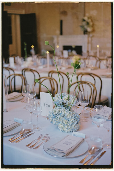 Close-up of floral centrepieces and menus at dinner tables.