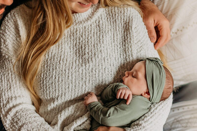 happy mom holding newborn in green  with luci levon photography