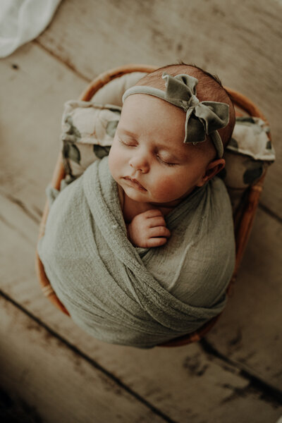 baby wrapped in sage blanket with sage headband  on small seat relaxed newborn photographer aberdeen