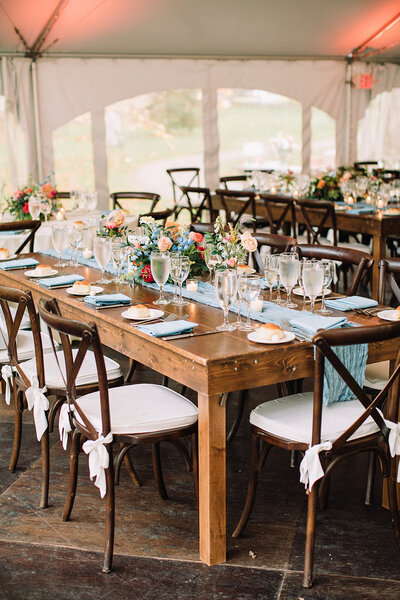 Beautiful outdoor wedding ceremony setup with floral aisle markers and a stunning arch of roses and greenery by Leigh Florist