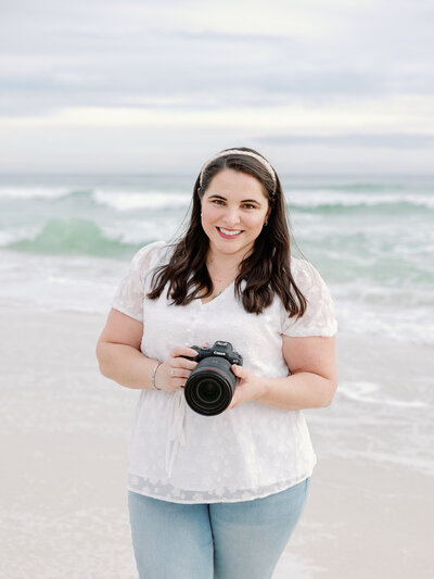 St. George  family photographer girl standing in the sand at sand hollow state park holding the camera and smiling