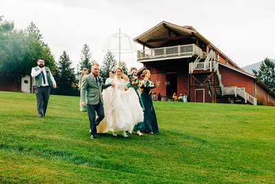 Bride and groom walking under umbrella at The Barn at Finley Point in Polson, MT
