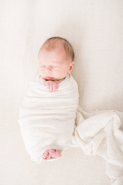 Boy in a wrap with toes sticking out captured by Niagara newborn photographer