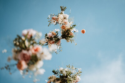 Wedding bouquets midair against blue sky, celebrating a joyful outdoor wedding in Breckenridge, Colorado.
