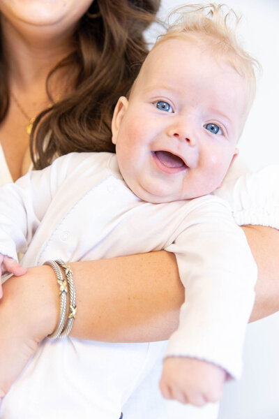 Baby smiling while being held in mother's arms